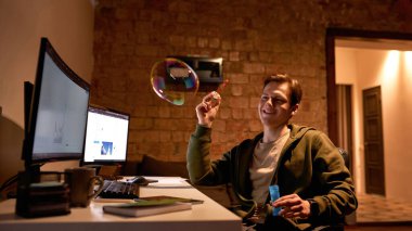 Gülümseyen erkek tüccar iş sırasında sabun köpüğü üflüyor.