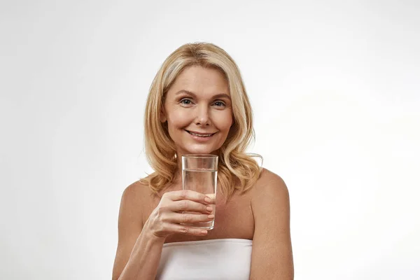 Sonriente mujer caucásica sosteniendo vidrio con agua — Foto de Stock