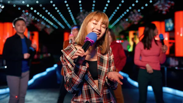 Asiática joven chica con amigos bailando y cantando en karaoke club — Foto de Stock