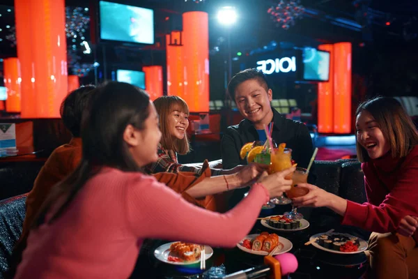 Asiático feliz grupo de amigos levantando copa de cócteles para tostadas en discoteca — Foto de Stock