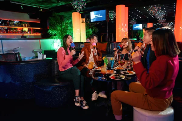 Grupp asiatiska killar och tjejer sjunger låtar på karaokeklubben — Stockfoto