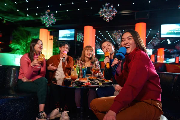 Asiatiska vänner som har kul medan de sjunger karaoke på kvällsfest i baren — Stockfoto