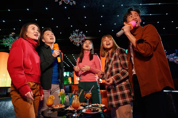 Los amigos asiáticos se divierten mientras cantan karaoke en la fiesta nocturna en el bar — Foto de Stock