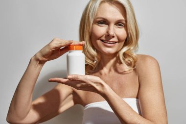 Kadının kısmi görüntüsü tıbbi haplarla dolu kavanozu gösteriyor