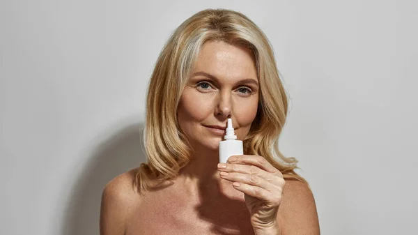 Mulher de meia idade gotejamento gotas nasais no nariz escorrendo — Fotografia de Stock