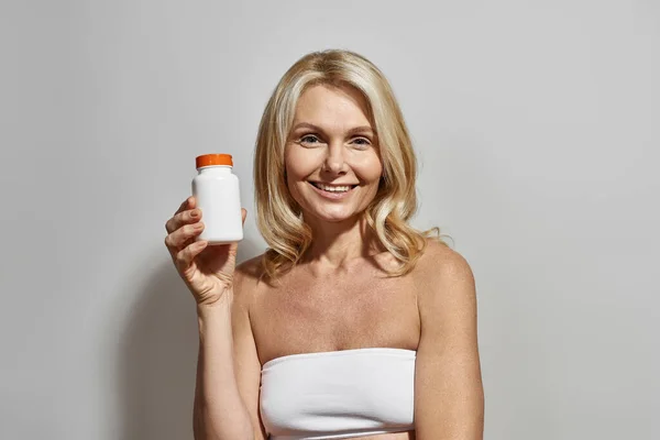 Smiling mature woman show jar with medical pills — Stock Photo, Image