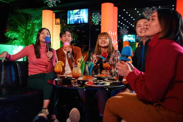 Alegre asiático amigos riendo y cantando canciones en karaoke club — Foto de Stock