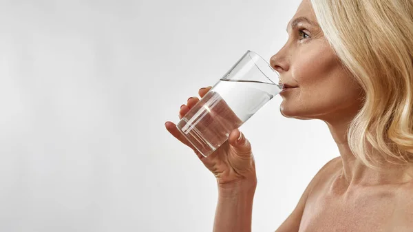 Reife kaukasische Frau trinkt Wasser aus Glas — Stockfoto