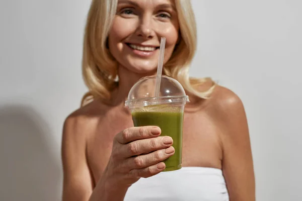 Souriant femme d'âge moyen boire smoothie vert — Photo
