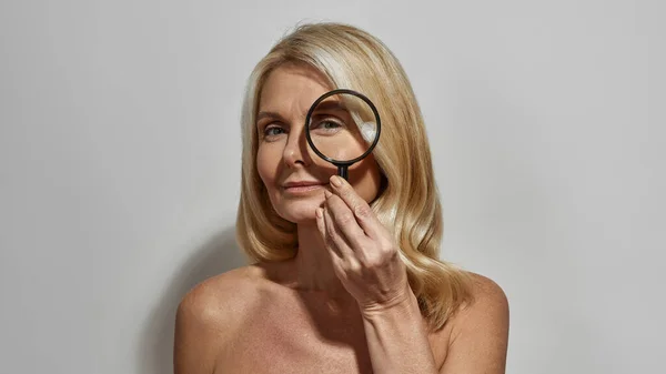 Woman looking at camera through magnifying glass — Stock Photo, Image