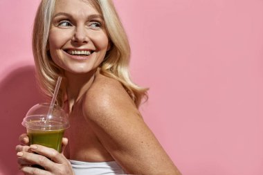 Olgun beyaz kadın kokteyl ya da meyve suyu içiyor.