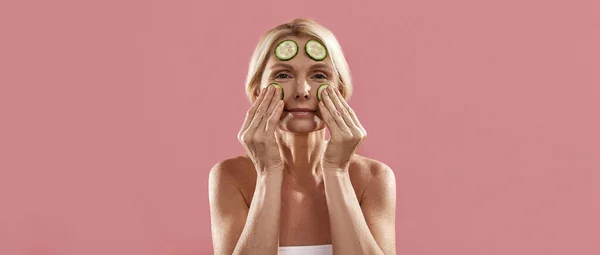 Wanita mengoleskan potongan mentimun organik di wajahnya — Stok Foto