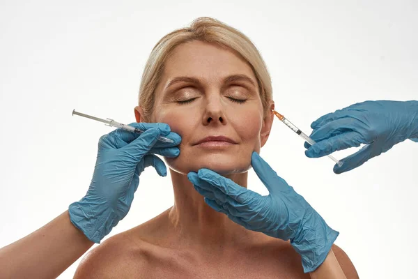 Lekarz ręce zrobić zastrzyk twarz kobiety w średnim wieku — Zdjęcie stockowe