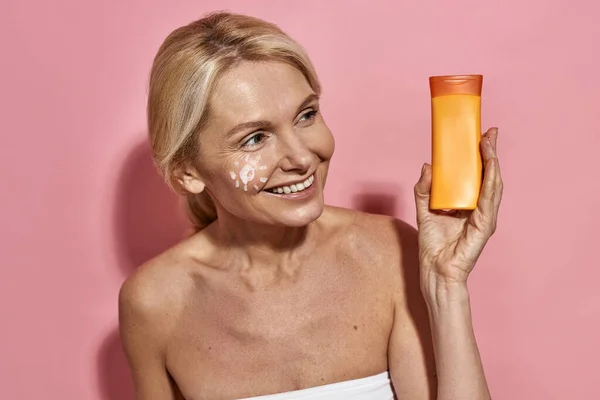 Middle aged caucasian woman holding sun cream — Stock Photo, Image