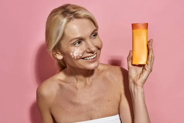 Kaukasische Frau mittleren Alters hält Sonnencreme in der Hand — Stockfoto