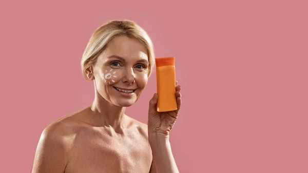 Mature woman with sun picture holding sun cream — Stock Photo, Image