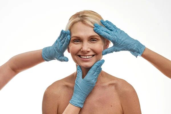 Cirurgiões plásticos tocam o rosto da mulher de meia-idade — Fotografia de Stock