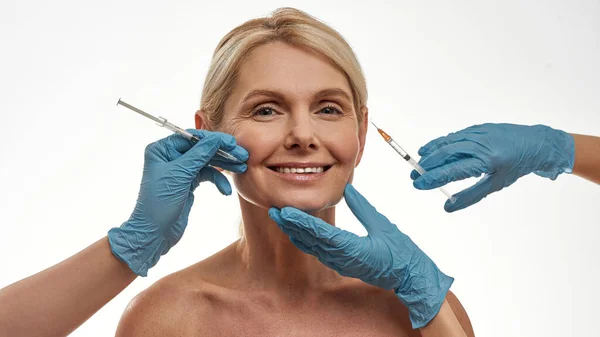 Lekarze wykonują wstrzyknięcie strzykawką na twarz kobiety — Zdjęcie stockowe