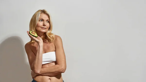 Mulher madura segurando frutas de abacate orgânico fatiado — Fotografia de Stock