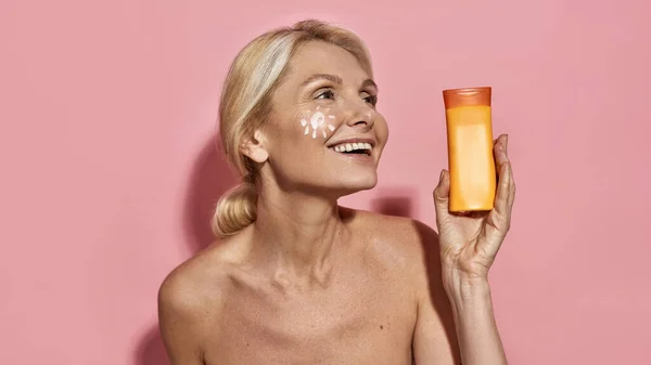 Pleased reif kaukasisch frau mit sonnencreme — Stockfoto