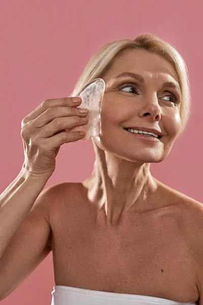 Mulher branca aplicando fatia de gelo em seu rosto — Fotografia de Stock
