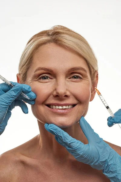 Médicos que fazem injeção no rosto de mulher madura — Fotografia de Stock