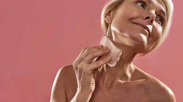 Mature caucasian woman applying ice slice on neck — Stock Photo, Image