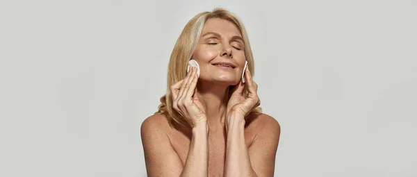 Mature woman smearing her face with cotton swabs — Stock Photo, Image