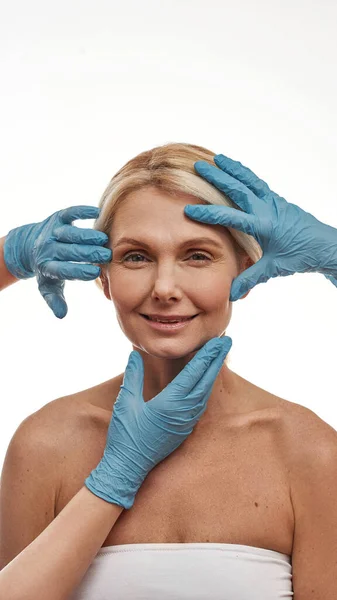 Chirurdzy plastyczni dotykają twarzy kobiety — Zdjęcie stockowe