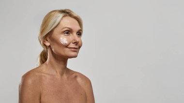 Yüzünde makyaj kremi olan bir kadın başka tarafa bakıyor.