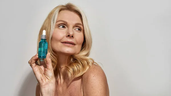 Frau hält Flasche mit Kosmetiköl in der Hand und zeigt sie — Stockfoto