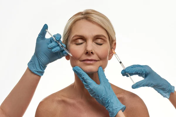 As mãos usam luvas para fazer injeção no rosto da mulher — Fotografia de Stock