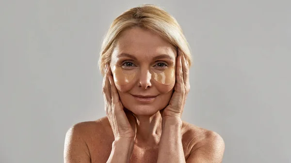 Mulher madura tocando rosto com sob manchas oculares — Fotografia de Stock