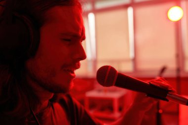 Bulanık evde mikrofonda şarkı söyleyen adam.