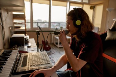 Erkek şarkıcı sesini evdeki bilgisayarda kaydediyor.