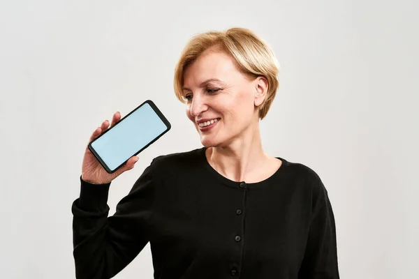 Donna sorridente che mostra e guarda lo smartphone — Foto Stock