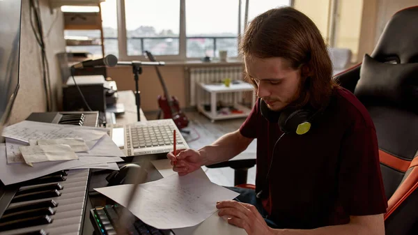 Άντρας τραγουδοποιός γράφει τραγούδι σε χαρτί στο στούντιο του σπιτιού — Φωτογραφία Αρχείου
