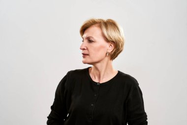 Odaklanmış orta yaşlı beyaz kadın başka tarafa bakıyor.