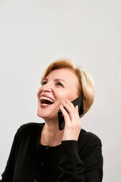陽気な中年女性話して上のスマートフォン — ストック写真
