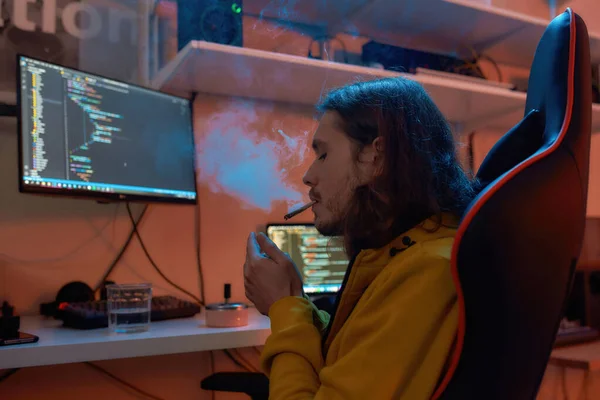 Άνδρας προγραμματιστής πληροφορικής ανάβει τσιγάρο ενώ εργάζεται — Φωτογραφία Αρχείου