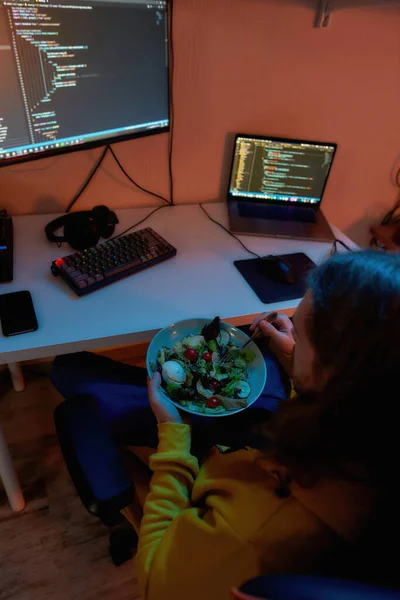 Desenvolvedor de TI masculino comendo salada durante a programação — Fotografia de Stock