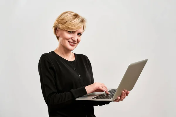 Donna sorridente utilizzando il computer portatile e guardando la fotocamera — Foto Stock