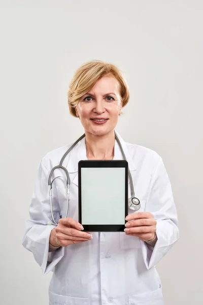 Mature female doctor hold and show digital tablet — Stock Photo, Image