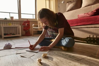 Genç Avrupalı adam kağıda şarkı metni yazıyor