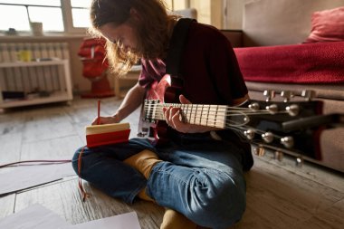 Gitar çalarken deftere yazan adam