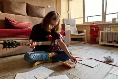 Elektro gitarda çalmadan önce notalara bakan adam