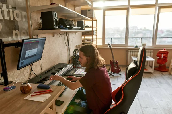 Ο άνθρωπος ηχογραφεί μουσική στον υπολογιστή ενώ παίζει πιάνο — Φωτογραφία Αρχείου