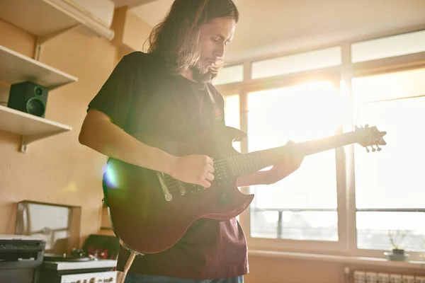 Young musician playing electric guitar at home