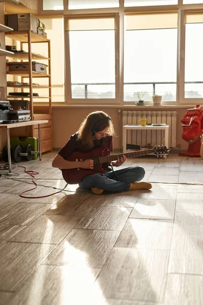 Hombre tocando riffs de guitarra eléctrica en el suelo en casa — Foto de Stock