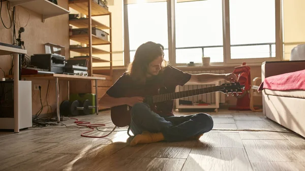 Hombre afinando la guitarra antes de tocar en el suelo en casa — Foto de Stock